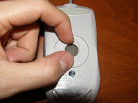 Foto de alguém removendo o trackball de um mouse de computador