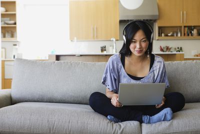 Mulher asiática no sofá com laptop conversando sobre VoIP