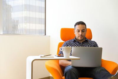 Homem usando laptop na cadeira laranja