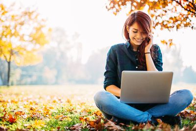Menina com computador durante o outono