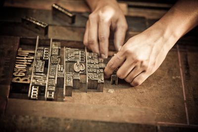 Um par de mãos organiza letras para impressão tipográfica