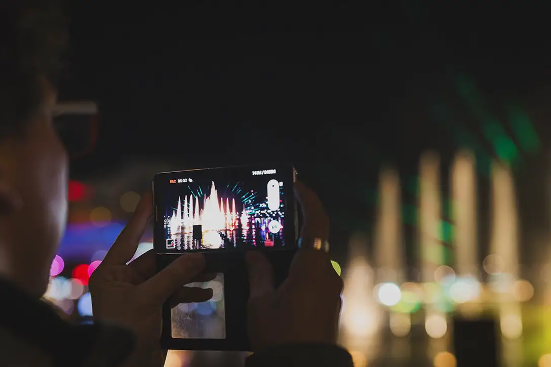 Pessoa segurando um iphone gravando vídeo à noite