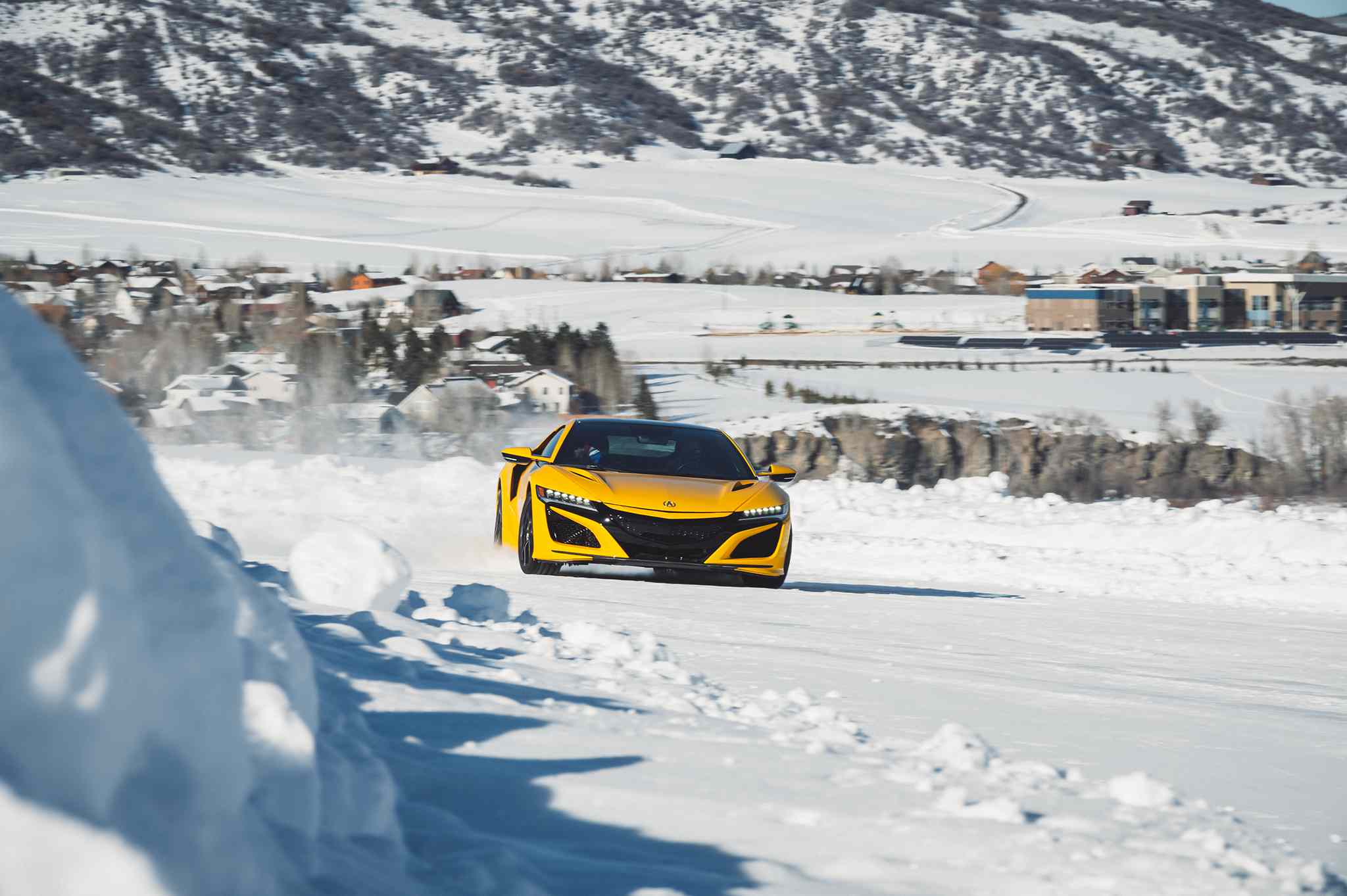 Um carro de teste Bridgestone amarelo dirigindo em um curso de neve para testar a tração dos pneus.