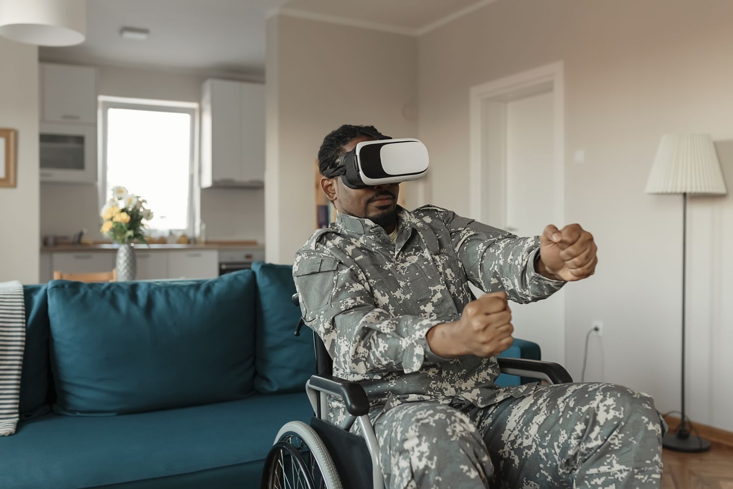 Um soldado uniformizado em uma cadeira de rodas usando óculos de realidade virtual e interagindo com o que está vendo.