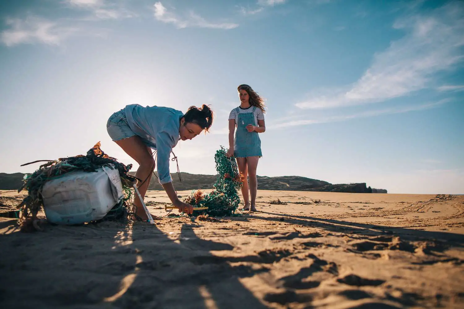 Duas mulheres coletando lixo na praia