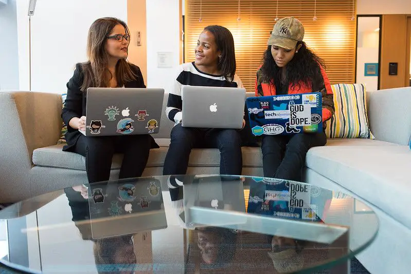 três mulheres trabalhando em um escritório em seus laptops